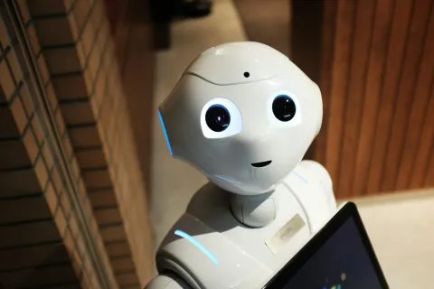 Roboter der ein Kindliches Gesicht hat und in die Kamera schaut.